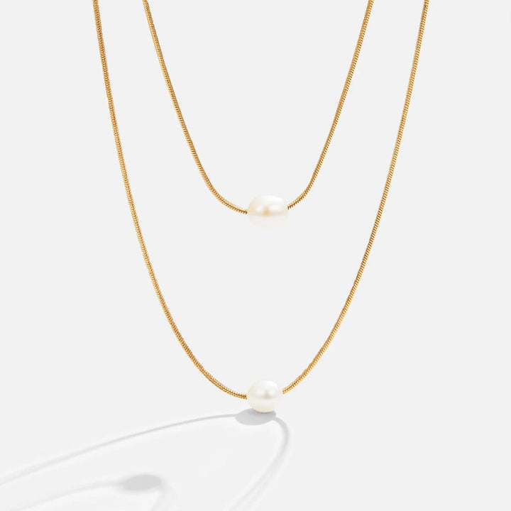 Sabine – Zweilagige goldene Kette mit dunklem Stein.